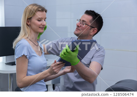 A dentist engaging with a patient, showcasing a caring and professional environment in a modern dental office, highlighting communication and patient care in dentistry. 128506474