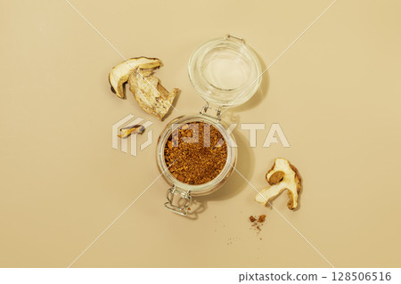 Mushroom products. Chaga powder in a glass jar with dry mushroom pieces on a beige background. Trendy Superfood. Home herbal apothecary concept. Flat lay 128506516