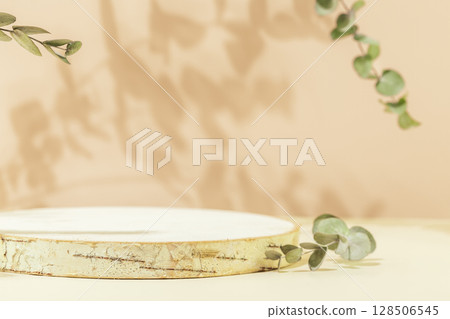 Wooden empty podium for presentation or advertising. Round product display on pink background with eucalyptus leaves and shadows. Concept of scene stage for natural products or promotion sale. Closeup Wooden empty podium for presentation or advertising. Round product display on pink background with eucalyptus leaves and shadows. Concept of scene stage for natural products or promotion sale. Closeup 128506545