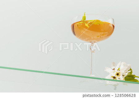 Wine glass of natural apple cider with mint and apple blossoms on glass shelf on blue background. Elegant glass with summer refreshing fermented low-alcohol fruit drink. low angle view, copy space 128506628