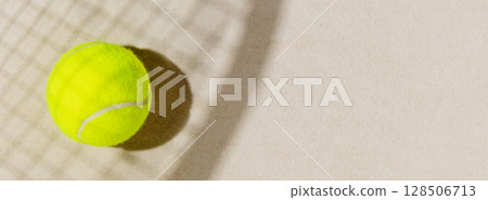 Tennis banner with tennis yellow ball on the sand beach with racket shadow. Tennis competitions, healthy sport and outdoor activities concept. Flat lay, banner size, copy space 128506713