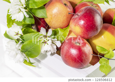 Natural red apples with blossom branch in wooden box. Concept of new crop and harvest. Seasonal, farm fruits. Close up Natural red apples with blossom branch in wooden box. Concept of new crop and harvest. Seasonal, farm fruits. Close up 128506812
