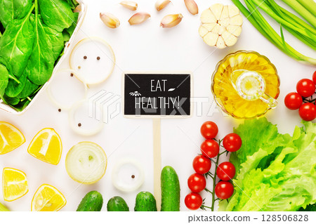 Healthy food. Organic, farm vegetables, olive oil and chalkboard with text Eat Healthy on white background. The concept of vegan diet and detox. Ingredients for vegetables salad. Flat lay 128506828