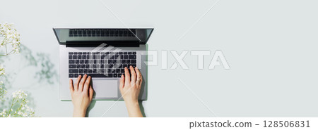 Romantic technology banner with womans hands working on laptop on blue background with flowers. Office desktop. Concept of working, communication, dating and online order on laptop. Copy space 128506831