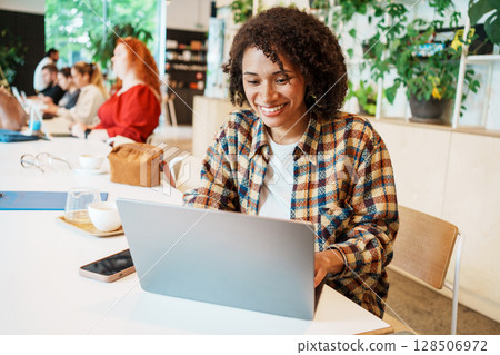 Young Woman Working in a Cozy Caf with Laptop 128506972