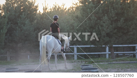 Horseback riding at sunset, an equestrian enjoying a tranquil ride in the paddock, surrounded by the beauty of nature and the calming atmosphere of the evening light Horseback riding at sunset, an equestrian enjoying a tranquil ride in the paddock, surrounded by the beauty of nature and the calming atmosphere of the evening light 128507760