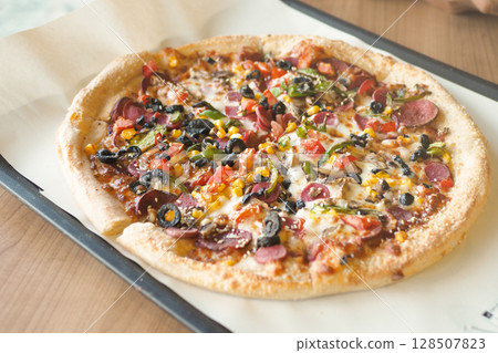 A Delicious Loaded Pizza with an Array of Toppings on a Wooden Table A Delicious Loaded Pizza with an Array of Toppings on a Wooden Table 128507823