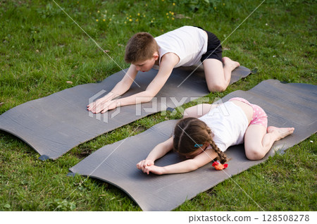 Children practicing yoga outdoors on mats. Healthy active lifestyle. 128508278