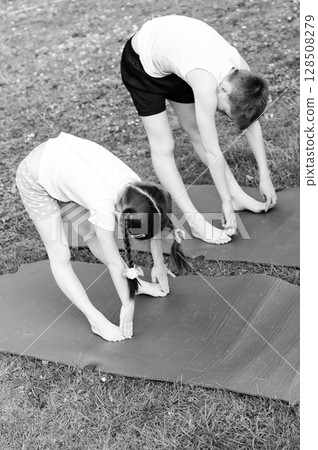 Children stretching outdoors on yoga mats. A healthy and active lifestyle. 128508279