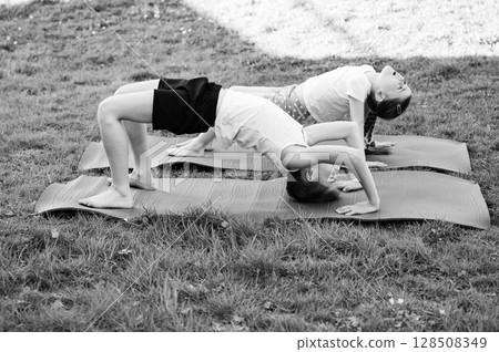 Kids practicing yoga outdoors on mats. A healthy and active lifestyle. 128508349