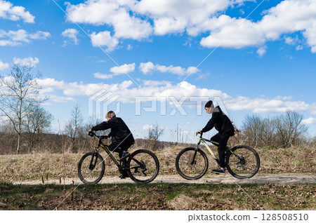 Two boys enjoy a sunny bike ride through a rural landscape. Blue skies and fluffy clouds provide a beautiful backdrop. Two boys enjoy a sunny bike ride through a rural landscape. Blue skies and fluffy clouds provide a beautiful backdrop. 128508510