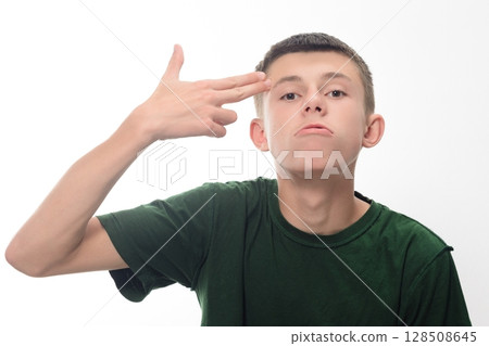 Teenage boy making a hand gesture, looking serious against a white background. Teenage boy making a hand gesture, looking serious against a white background. 128508645
