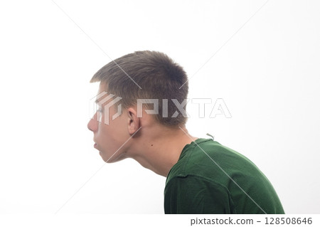 Profile view of a teenage boy with short brown hair, wearing a dark green shirt against a white background. Profile view of a teenage boy with short brown hair, wearing a dark green shirt against a white background. 128508646