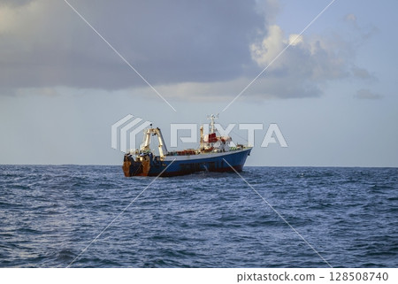 Fishing vessel is conducting an industrial catch of wild marine products using deep-sea trawl. 128508740