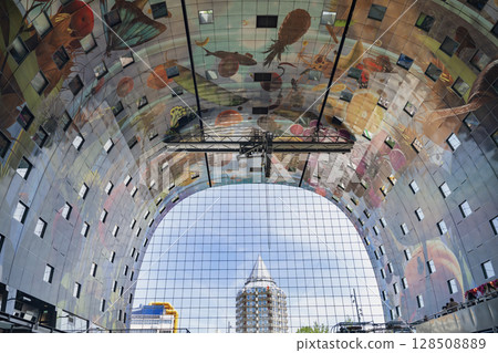 Rotterdam, Netherlands - July 12, 2025. A lively scene inside Markthal Rotterdam with diverse food stalls, neon signage, and international visitors exploring the iconic indoor market. 128508889