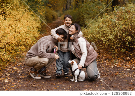Happy family of three with dog in autumn park Happy family of three with dog in autumn park 128508992