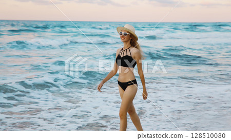 Summer vacation, happy slim woman walking running on sea beach, coast with waves 128510080