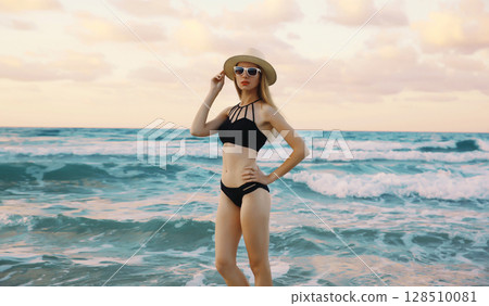 Summer vacation, beautiful young woman in swimsuit, hat standing on sea beach background Summer vacation, beautiful young woman in swimsuit, hat standing on sea beach background 128510081