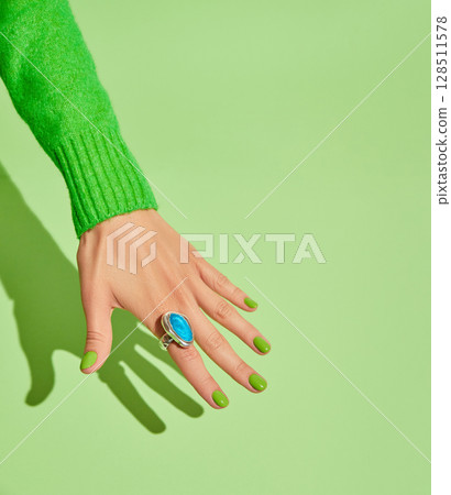 Beautiful womans hands with spring autumn nail design on green background. Manicure, pedicure beauty salon concept Beautiful womans hands with spring autumn nail design on green background. Manicure, pedicure beauty salon concept 128511578
