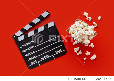 Striped box with popcorn and clapperboard on a red background 128511582