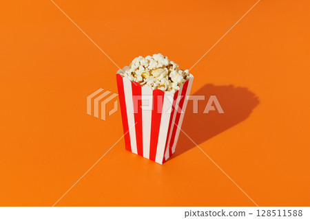 Striped box with popcorn on an orange background 128511588