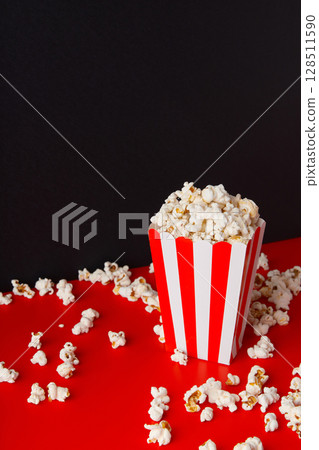 Striped box with popcorn on a red and black background 128511590