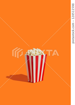 Striped box with popcorn on an orange background 128511598