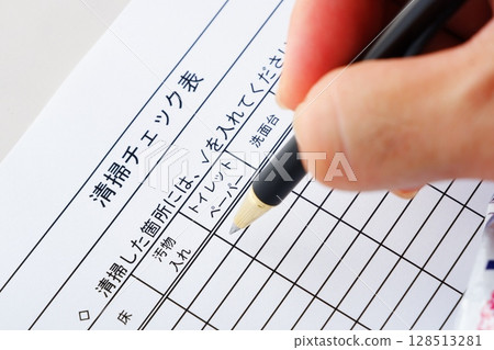 In the cleaning and building maintenance industries, filling out a cleaning checklist after cleaning a toilet 128513281