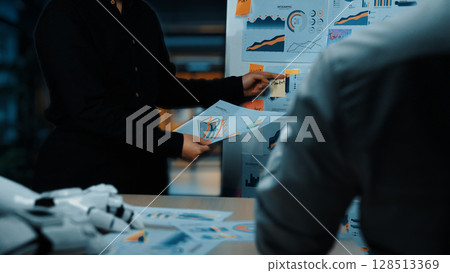 Business meeting showcasing data analysis with graphs and charts, professionals discussing statistics on printed reports in a modern office environment. Noogenesis 128513369