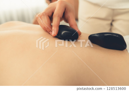 Closeup hot stone massage at spa salon in luxury resort. Quiescent Closeup hot stone massage at spa salon in luxury resort. Quiescent 128513600