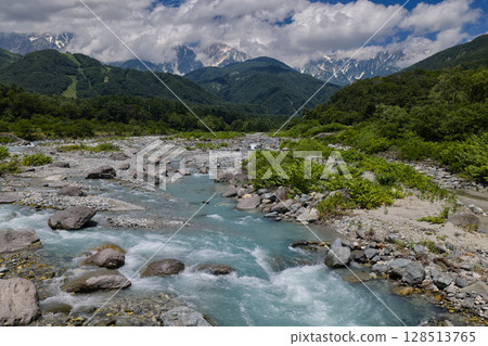 The beautiful flow of the Matsukawa River and the Hakuba Mountain Range between the clouds. The flow and the Hakuba Mountain Range between the clouds (aerial shot by drone) 128513765