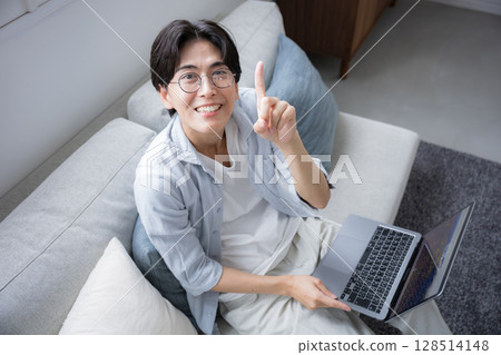 俯視圖：一位男士在客廳使用電腦，正看著鏡頭。推薦姿勢 128514148