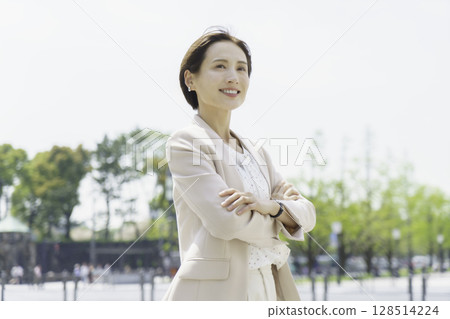 一位年輕女商人雙手交叉站在戶外的畫像 128514224