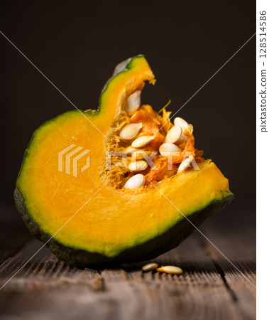 Slice of green pumpkin with orange flesh and visible seeds 128514586
