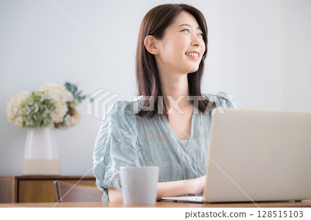 穿著休閒服的年輕可愛女子在家裡的房間裡用筆記型電腦抬頭 128515103