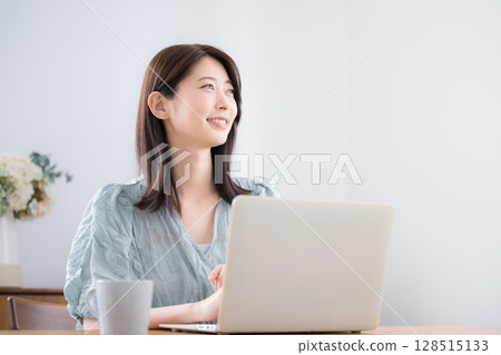 Young cute casual clothing woman using a laptop in her home room, looking up Young cute casual clothing woman using a laptop in her home room, looking up 128515133