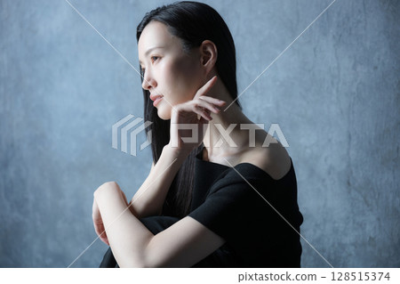 A beauty woman with a gray background holding her knees and thinking. Image of depression, etc. 128515374