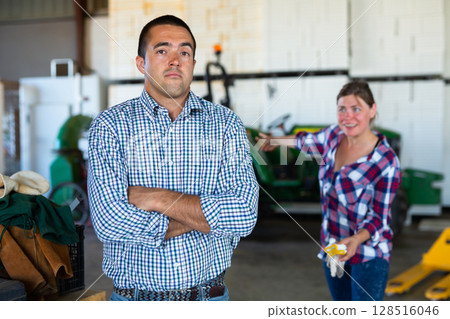 Dissatisfied female farmer talking to shrugging workman 128516046