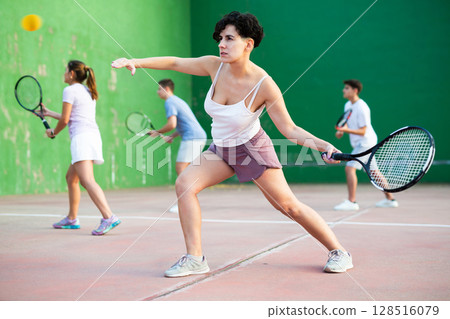 Young hispanic woman playing frontenis on open court in summer Young hispanic woman playing frontenis on open court in summer 128516079