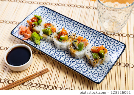 On blue and white plate there is Saketaki roll of crab, avocado, cucumber and salmon 128516091