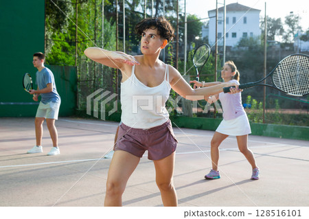 Expressive resolved fit girl playing frontenis ball friendly match on court 128516101