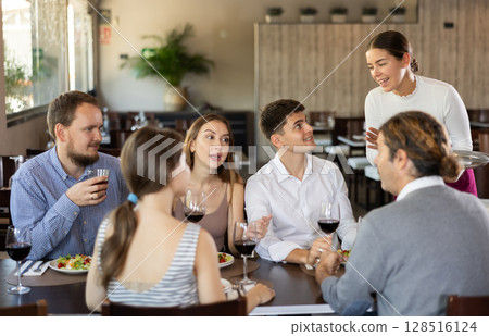 Female waitress taking order from group of friends in restaurant 128516124