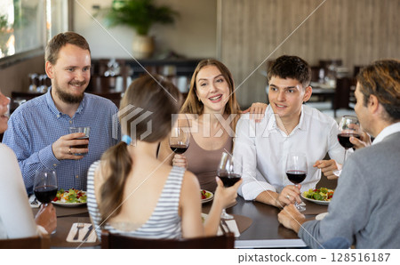 Group of friends talking and eating in restaurant 128516187