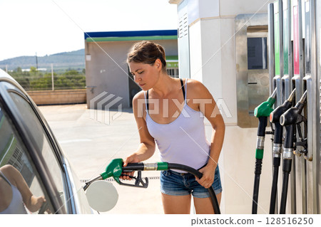 Woman refuelling her car at petrol filling station 128516250