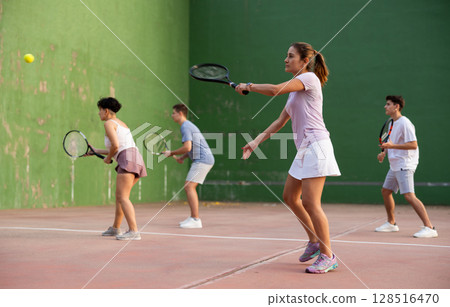 Woman pelota player hitting ball with racket 128516470