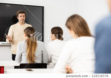 Knowledgeable professor explaining subject to classroom full of students 128516576