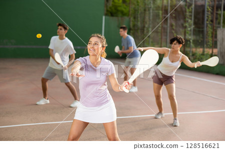 Woman serving ball during frontenis game outdoors Woman serving ball during frontenis game outdoors 128516621