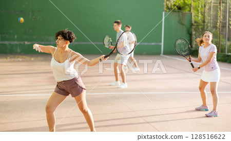 Woman playing frontenis with partners at sunny day, healthy lifestyle concept 128516622