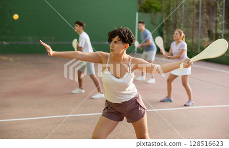 Young Latina playing pelota on open court on summer day Young Latina playing pelota on open court on summer day 128516623