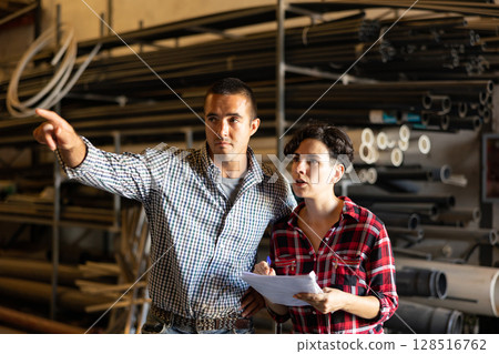 Manager and hired worker conduct an inventory in the warehouse of building materials Manager and hired worker conduct an inventory in the warehouse of building materials 128516762